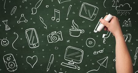 A person drawing media and communication icons on school blackboard with chalk