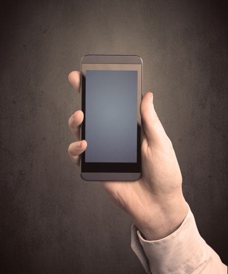 Caucasian hand in business suit holding a blank screen smartphone