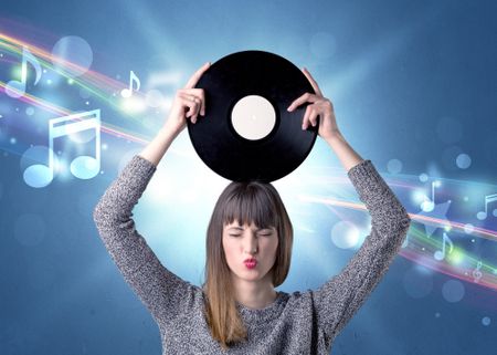 Young lady holding vinyl record on a blue background with musical notes behind her