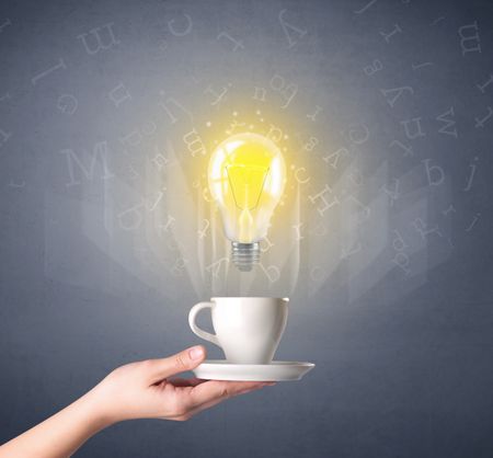 Young female hand holding coffee cup with a lightbulb and alphabet letters above it