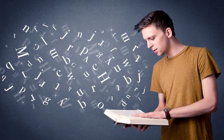 Casual young man holding book with white letters flying out of it