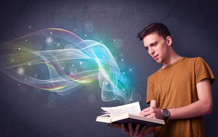Casual young man holding book with rainbow waves flying out of it