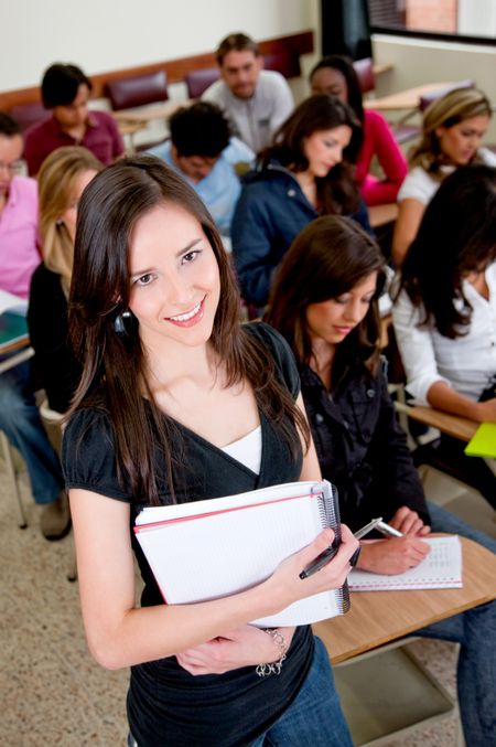 Female student in the classroom with a notebook and smiling