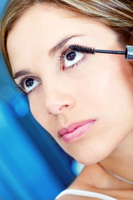 Beautiful woman putting mascara on her eyes - make up concepts