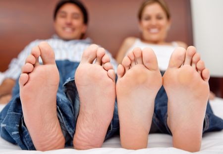 Happy couple lying on the bed barefoot