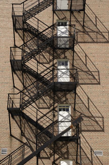 Multistory fire escape with afternoon shadows on exterior brick wall