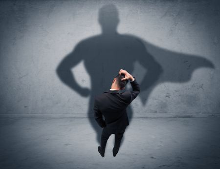 A confident young elegant salesman with briefcase facing a wall, looking at his superman shadow concept