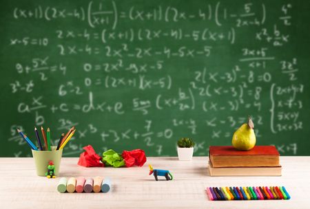 Back to school concept with long numbers calculation on blackboard and a desk with books, fruit