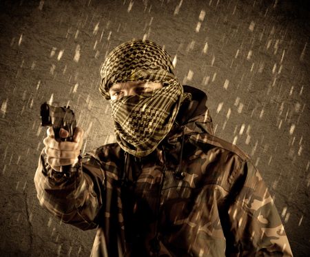 Portrait of dangerous heavily armed terrorist soldier with mask on grungy rainy background 