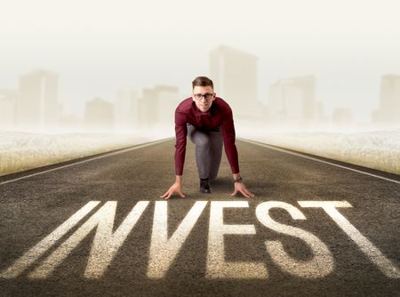 Young determined businessman kneeling before invest sign