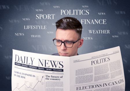 Young smart businessman reading daily newspaper