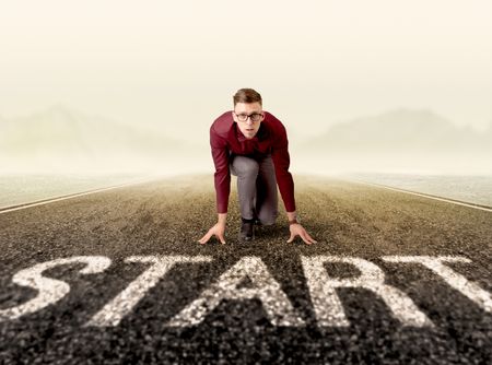 Young determined businessman kneeling at a start line 