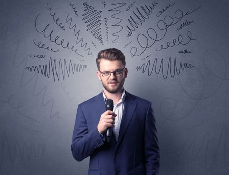 Businessman speaking into microphone with scribbles over his head 