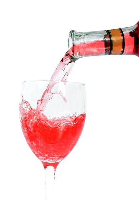 Pouring red wine on a glass close-up over a white backgrund