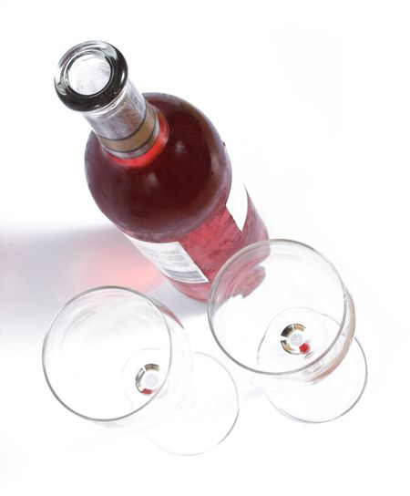 Glasess and botlle of red wine from the top over a white background
