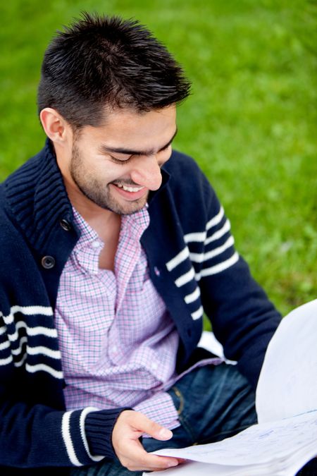 Male student outdoors reading from a notebook