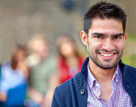 Man smiling outdoors with a group of people on the background