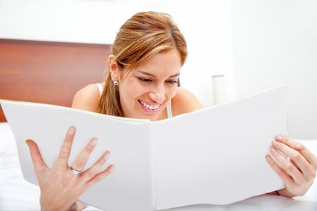 Woman relaxing at home reading a book on the bed