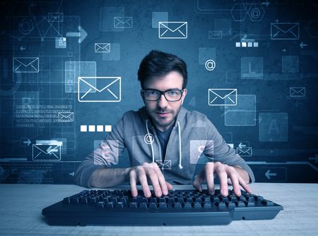 A talented young hacker hacking email address passwords concept with keyboard on desk and illustrated letters in the background