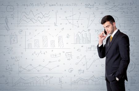A confident young businessman standing in front of wall with drawn pie charts, graphs, numbers, arrows concept