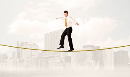 A young elegant businessman walking on tight golden rope in front of city buildings landscape background concept