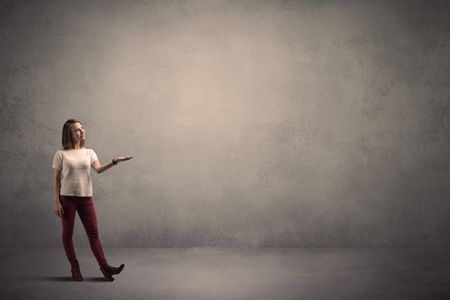 Caucasian woman standing in front of a blank grunge wall