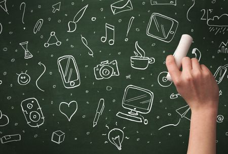 A person drawing media and communication icons on school blackboard with chalk