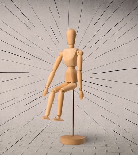 Wooden mannequin posed in front of a greyish background with black lines around him