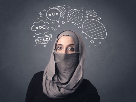 Young muslim woman wearing niqab with drawn speech bubbles above her head