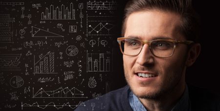 Portrait of a young businessman with charts and graphs scribbled next to him on a dark background