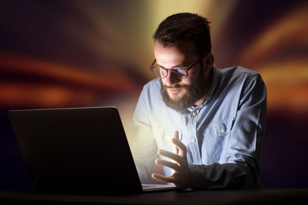 Young handsome businessman working late at night in the office with warm lights in the background