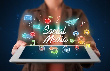 Casual young woman holding tablet with social media icons