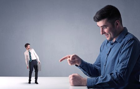 Young professional businessman being angry with an other miniature businessman