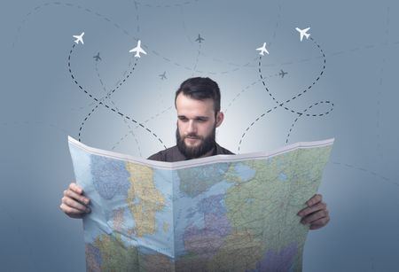 Handsome young man holding a map with little planes and their paths above him 