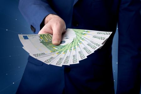 young-businessman-holding-large-amount-bills-608769611 Young businessman holding large amount of bills with light beams behind him