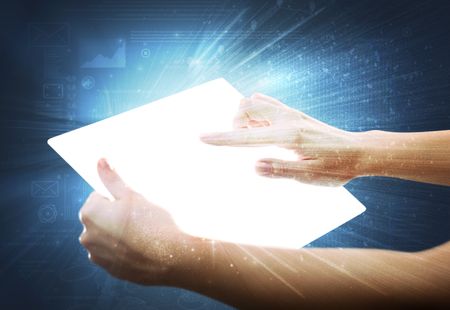 Young female hand holding a tablet with faded charts in the background