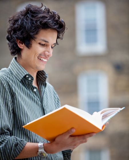 Male student outdoors holding a notebook and smiling