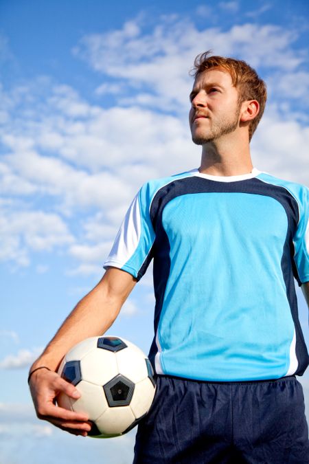 Handsome European man holding a football outdoors