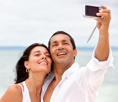 Couple at the beach smiling to the camera, taking a self portrait