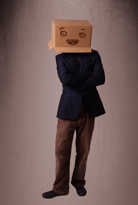 Young man standing and gesturing with a cardboard box on his head with smiley face