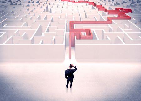 A businessman in suit giving thumbs up in front of labyrinth with red line showing the way out