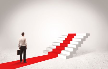 A successful businessman with briefcase standing on red carpet in front of steps in white space concept