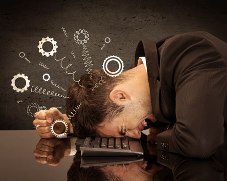 Falling apart illustration concept with cranks, cog wheels springing from a fed up and tired businessman's head resting on laptop keyboard