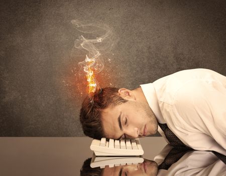 A frustrated businessman resting his head on a keyboard and shouting with his hair on smoke, catching fire