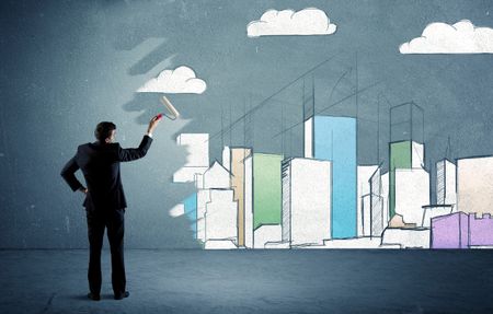 An elegant businessman standing with a paint roller transforming a blue wall into urban city landscape drawing sketch including skyscrapers and clouds concept