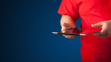 Close up of hand holding digital touchpad tablet device on background