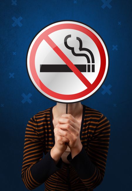 Casual young woman holding round sign with no smoking graphic