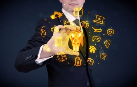 An office salesman promoting his bright ideas concept with illustration of online media and device logos around electric glass light bulb.
