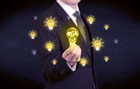 A creative businessman has a bright idea concept with office worker holding light bulb in foreground.