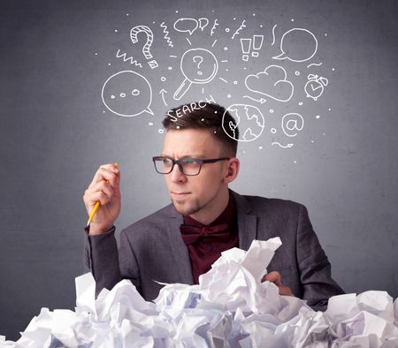 Young businessman sitting behind crumpled paper with mixed doodles over his head